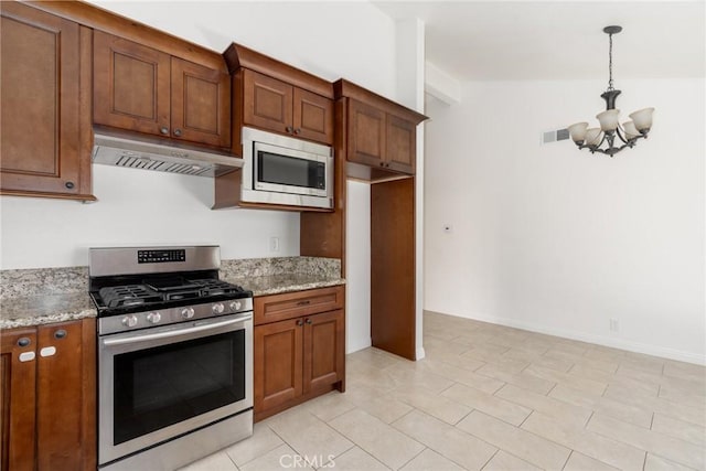 kitchen with under cabinet range hood, stainless steel appliances, an inviting chandelier, and brown cabinetry