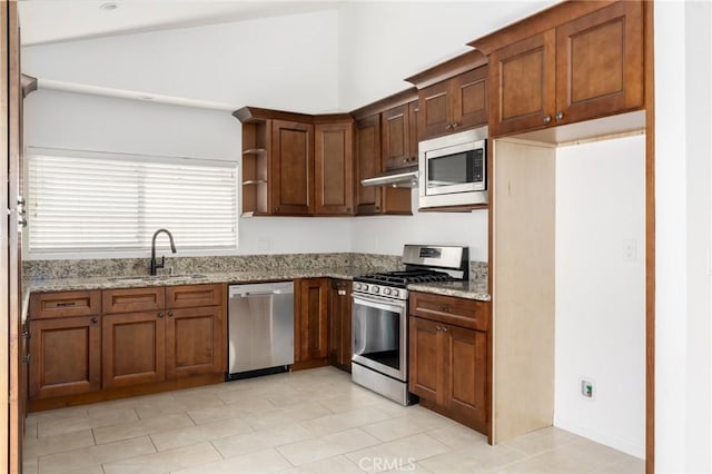 kitchen with light stone counters, stainless steel appliances, a sink, vaulted ceiling, and open shelves