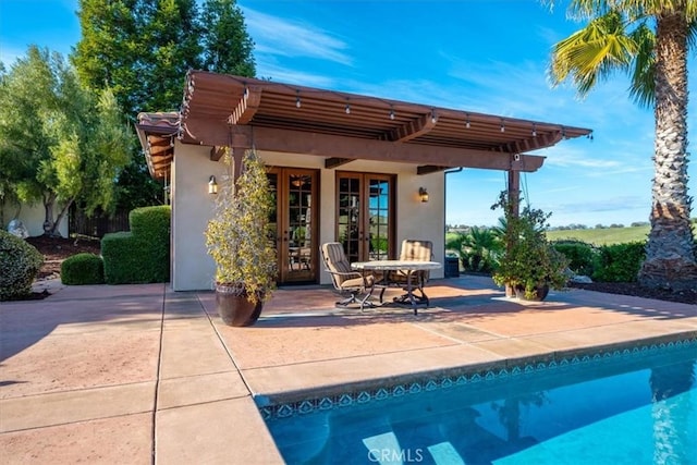 rear view of property featuring a patio, french doors, an outdoor pool, and stucco siding