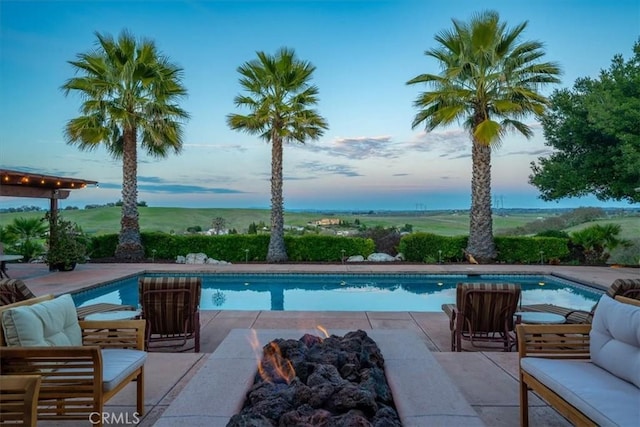 pool at dusk with an outdoor hangout area, a patio area, and an outdoor pool