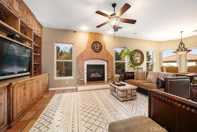 living area featuring light tile patterned floors, visible vents, baseboards, a ceiling fan, and a fireplace