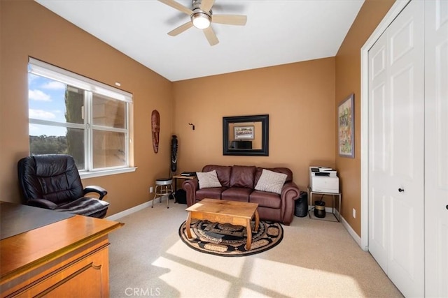 living area featuring baseboards, a ceiling fan, and light colored carpet