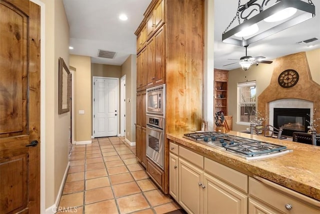 kitchen with stainless steel appliances, a large fireplace, visible vents, and light tile patterned floors