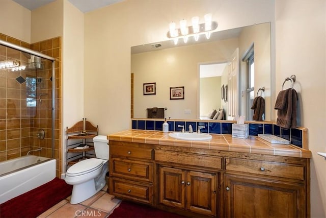 bathroom with bath / shower combo with glass door, visible vents, toilet, vanity, and tile patterned floors