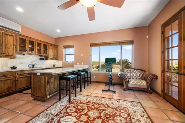 kitchen featuring brown cabinetry, glass insert cabinets, a breakfast bar area, and backsplash