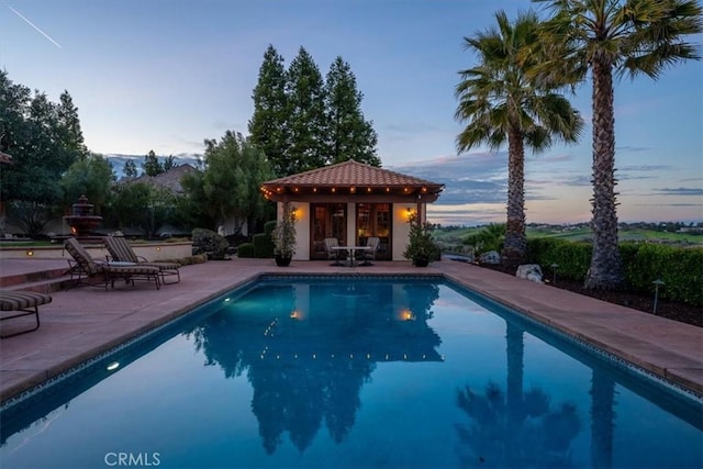 pool with a patio area, an outdoor structure, and a storage structure