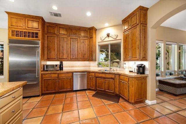 kitchen with appliances with stainless steel finishes, brown cabinets, visible vents, and light tile patterned floors