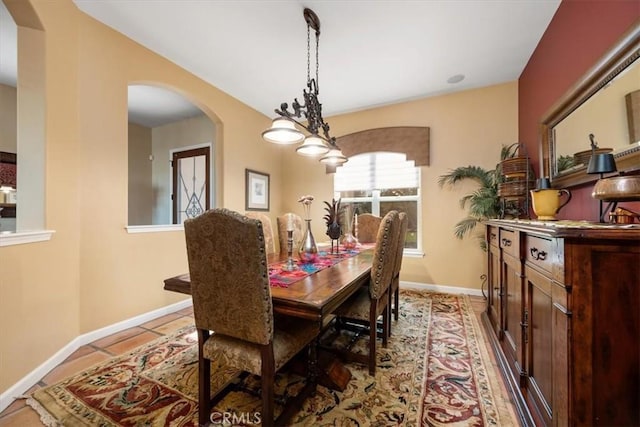 dining space featuring arched walkways, baseboards, and tile patterned floors