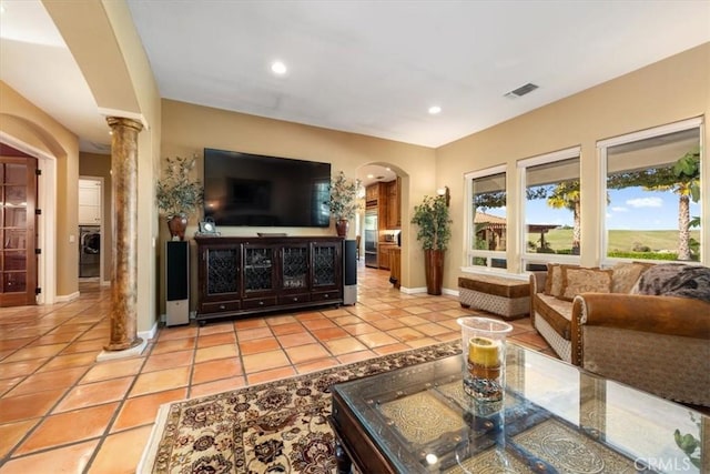 living room featuring light tile patterned floors, decorative columns, visible vents, arched walkways, and recessed lighting