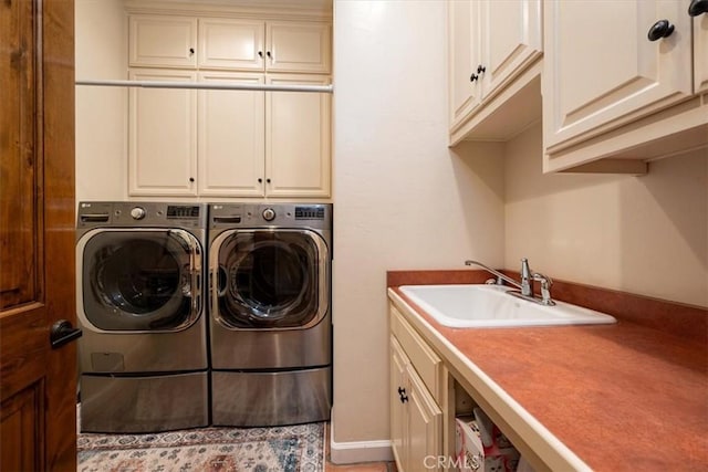 clothes washing area with independent washer and dryer, cabinet space, and a sink