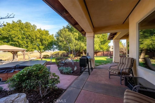 view of patio featuring a hot tub, fence, area for grilling, and a gazebo