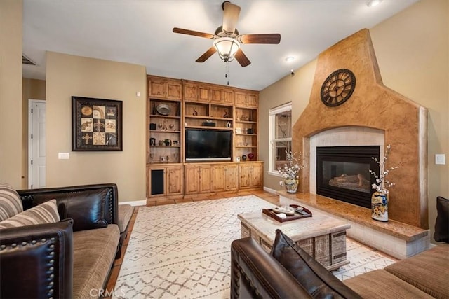 living room featuring ceiling fan, a premium fireplace, visible vents, and baseboards