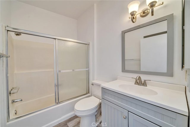 full bath featuring wood finished floors, vanity, toilet, and bath / shower combo with glass door