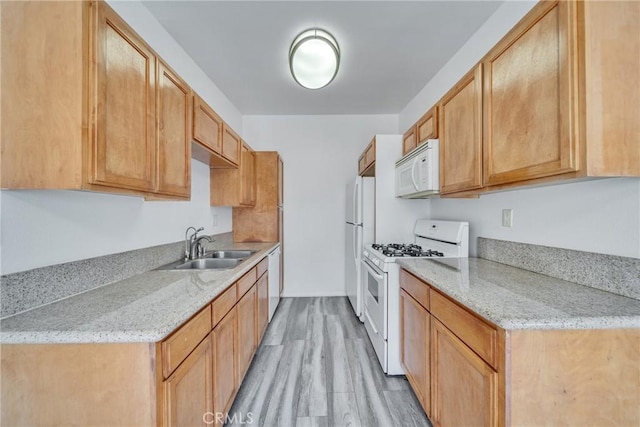 kitchen featuring white appliances, a sink, light wood-style flooring, and light stone countertops