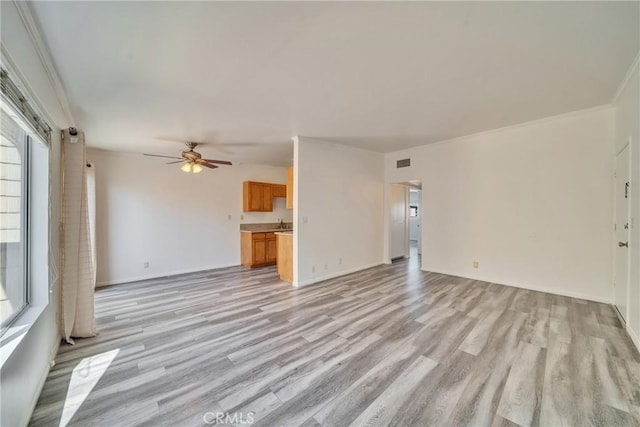 unfurnished living room featuring ceiling fan, visible vents, light wood-style flooring, and crown molding