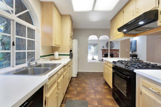 kitchen with light brown cabinetry, gas stove, a sink, and under cabinet range hood