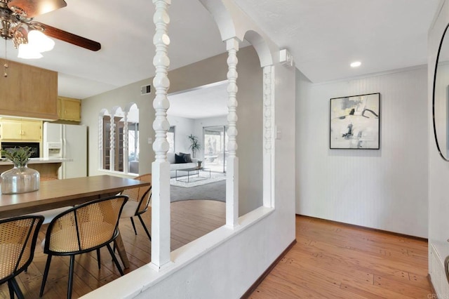 dining area with arched walkways, decorative columns, light wood finished floors, visible vents, and a ceiling fan