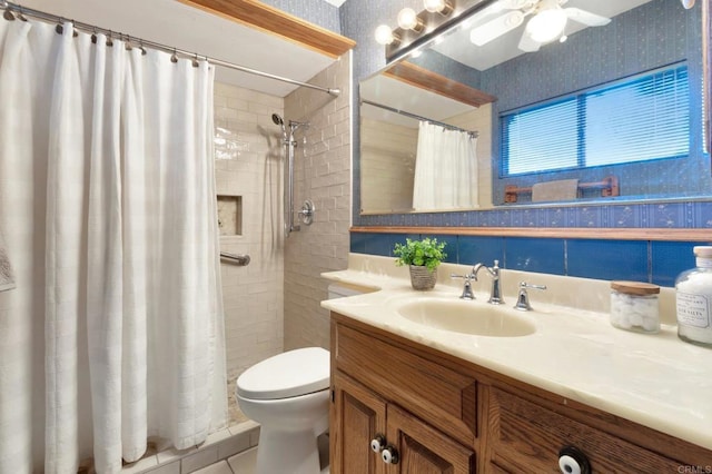 bathroom with tiled shower, vanity, toilet, and wallpapered walls