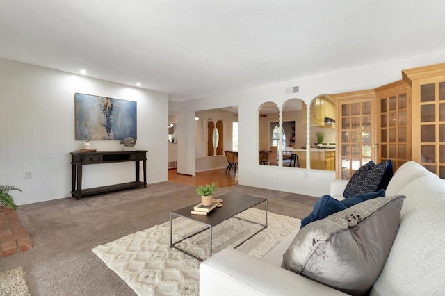 living area with arched walkways, carpet floors, visible vents, and recessed lighting