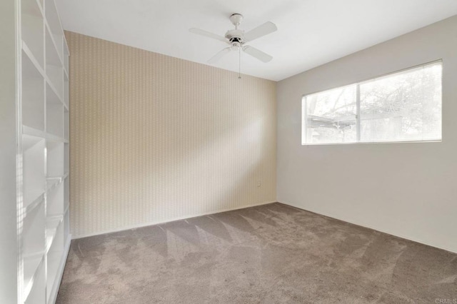 carpeted empty room with a ceiling fan and wallpapered walls