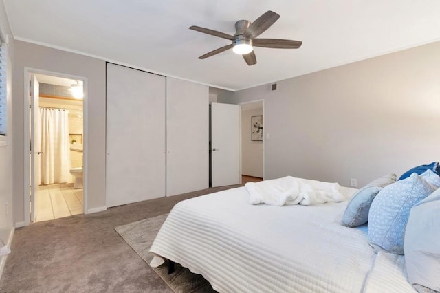 carpeted bedroom featuring a closet, visible vents, a ceiling fan, ornamental molding, and ensuite bath