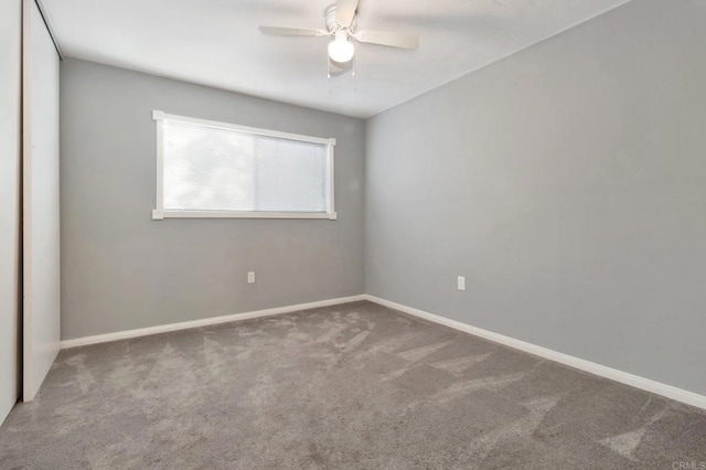 carpeted spare room with a ceiling fan and baseboards