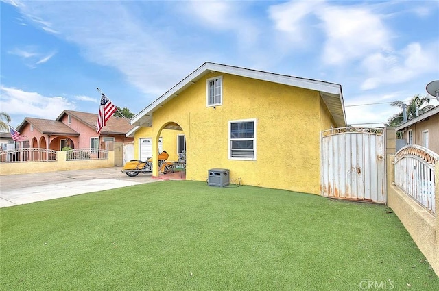 back of property featuring a lawn, a gate, fence, a patio area, and stucco siding