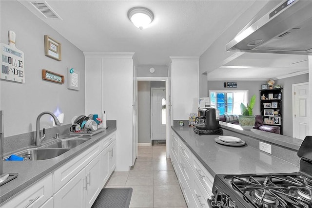 kitchen featuring light tile patterned floors, black range with gas cooktop, a sink, visible vents, and range hood