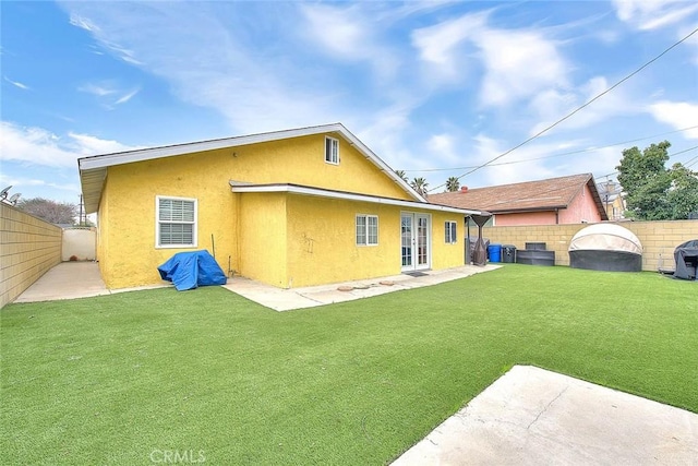 back of house with a fenced backyard, a lawn, and stucco siding