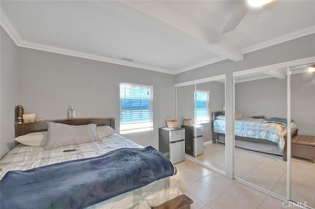 bedroom featuring beam ceiling, light tile patterned floors, multiple closets, visible vents, and freestanding refrigerator