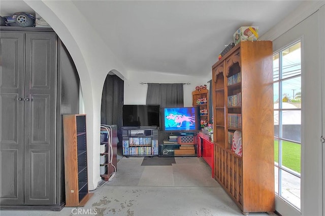 living room featuring arched walkways, a wealth of natural light, and concrete flooring