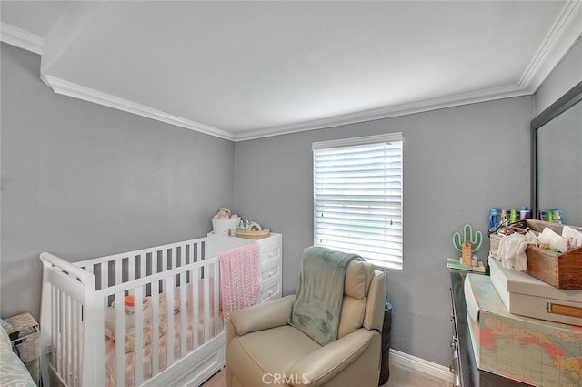 bedroom featuring baseboards, a nursery area, and crown molding