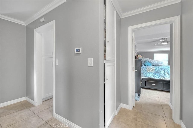 corridor with light tile patterned floors, baseboards, and crown molding