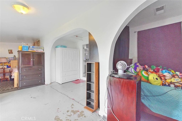 bedroom featuring concrete flooring, arched walkways, and visible vents