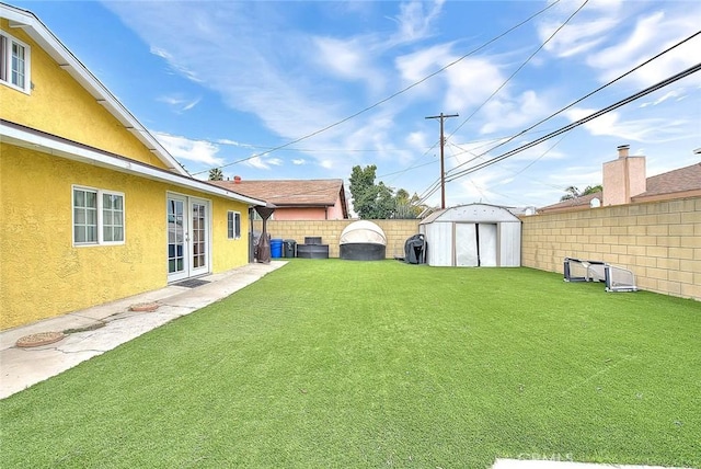 view of yard featuring french doors, a storage unit, an outdoor structure, and a fenced backyard