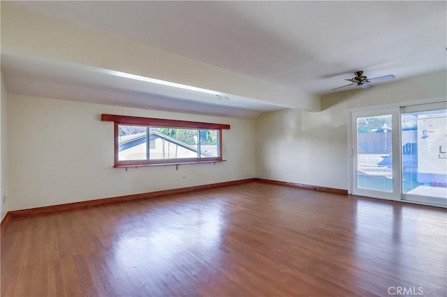 unfurnished room featuring ceiling fan, wood finished floors, and baseboards