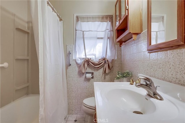 bathroom featuring tile patterned flooring, a sink, toilet, and tile walls