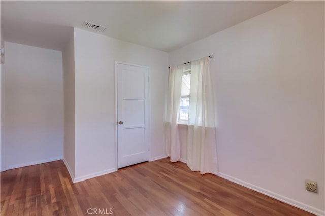 empty room with visible vents, baseboards, and wood finished floors