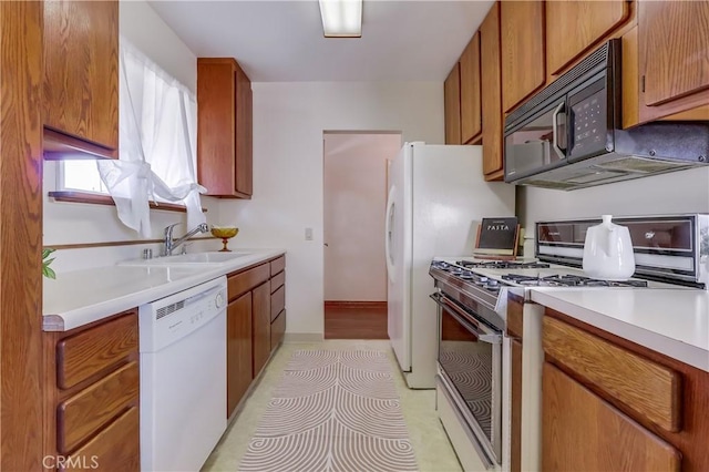 kitchen featuring black microwave, white dishwasher, a sink, brown cabinetry, and gas range oven