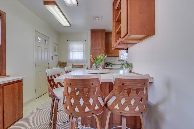 kitchen with light countertops, brown cabinetry, open shelves, and visible vents