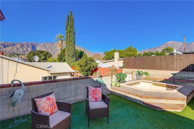 view of patio featuring a fenced backyard, a mountain view, and an in ground hot tub