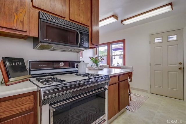 kitchen featuring black microwave, light countertops, brown cabinets, and range with gas stovetop