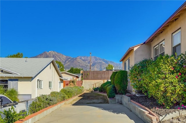 view of side of property featuring a patio, fence, a mountain view, and stucco siding