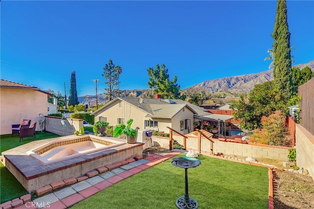 view of yard with a patio area, a fenced backyard, a mountain view, and an in ground hot tub