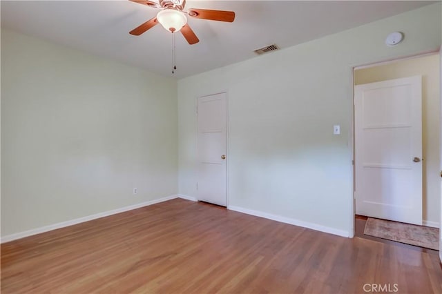 spare room with light wood finished floors, baseboards, visible vents, and ceiling fan