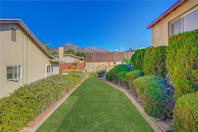 view of yard featuring fence and a mountain view