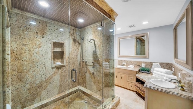 bathroom featuring double vanity, visible vents, a sink, a shower stall, and tile walls