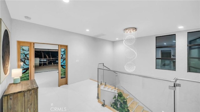 hall with recessed lighting, a chandelier, and an upstairs landing