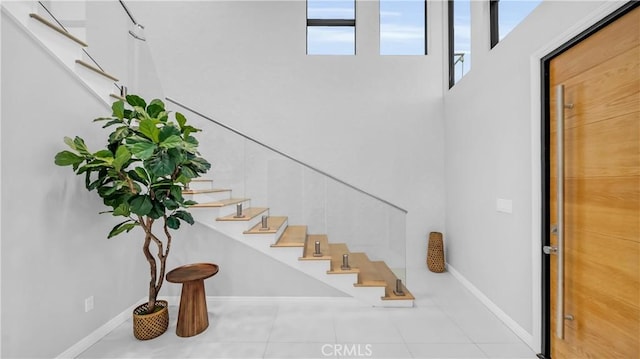 staircase with baseboards and tile patterned floors