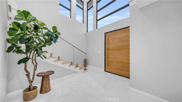 stairs featuring baseboards, a high ceiling, and tile patterned flooring